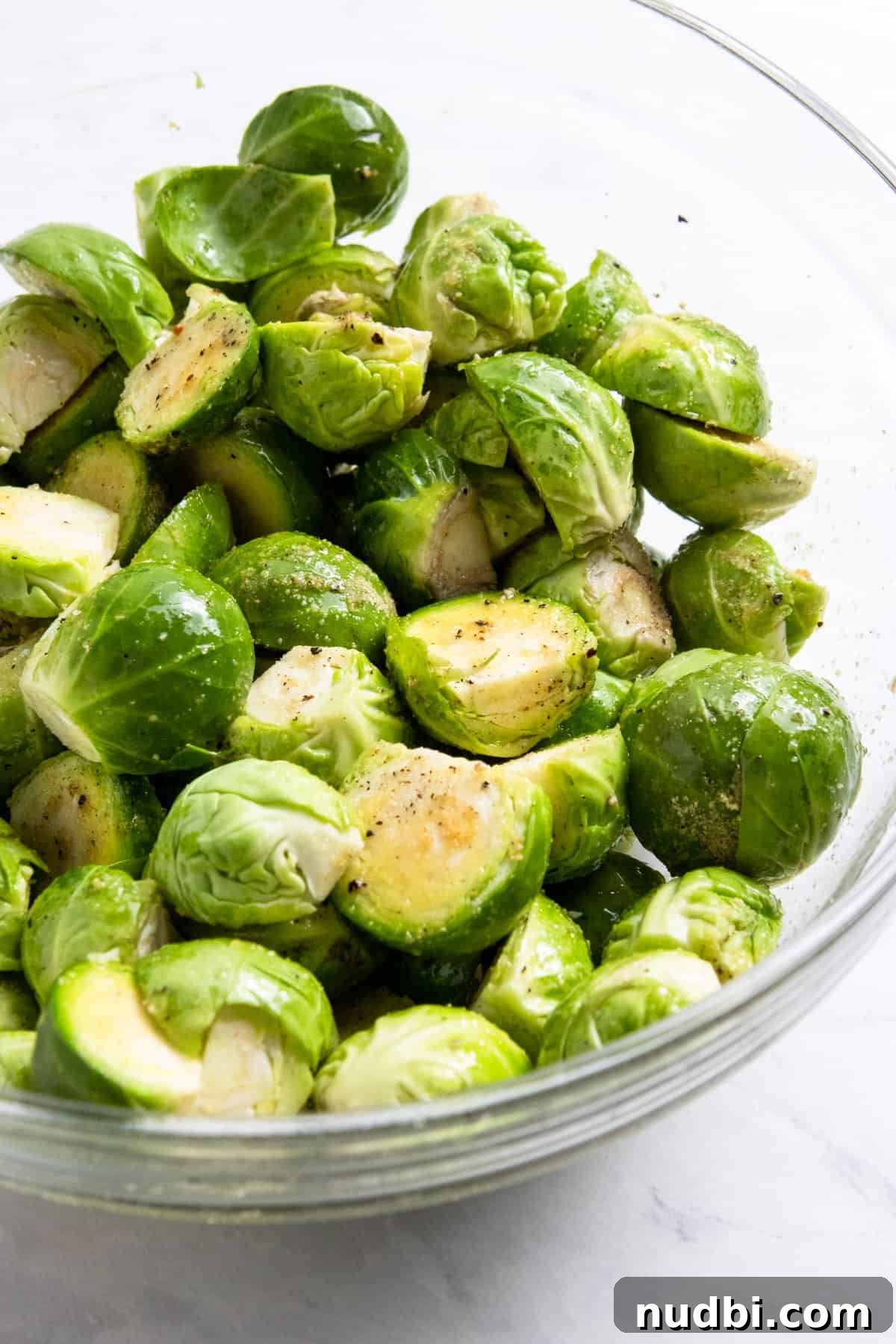 25 Delicious Pairings for Brussels Sprouts to Complete Any Meal 3 Glass bowl with brussels sprouts tossed in olive oil and seasonings.