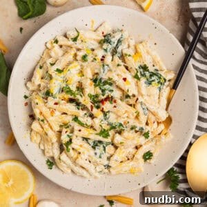 Plate with creamy pasta topped with chopped parsley and lemon zest.