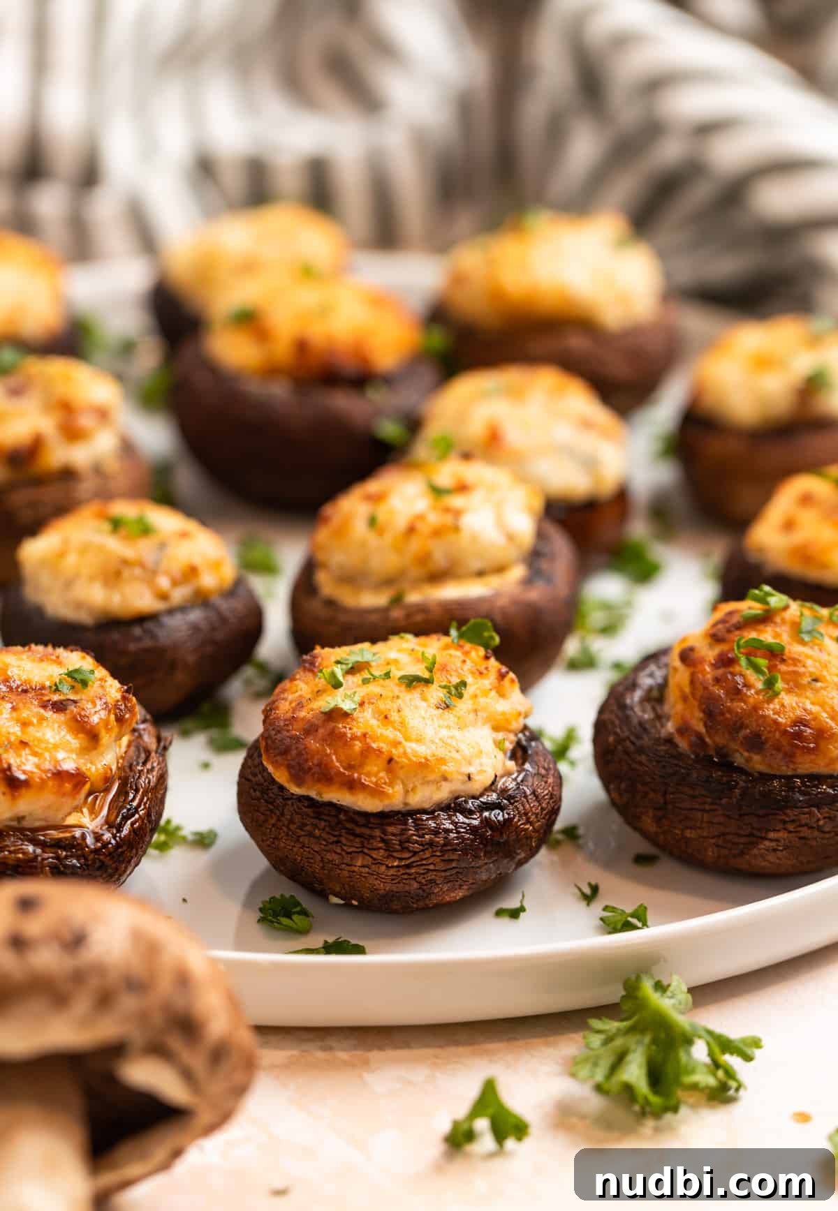 Crispy Air Fryer Stuffed Mushrooms Recipe for Quick Appetizers 3 Stuffed baby bella mushrooms with parsley garnish on white plate.