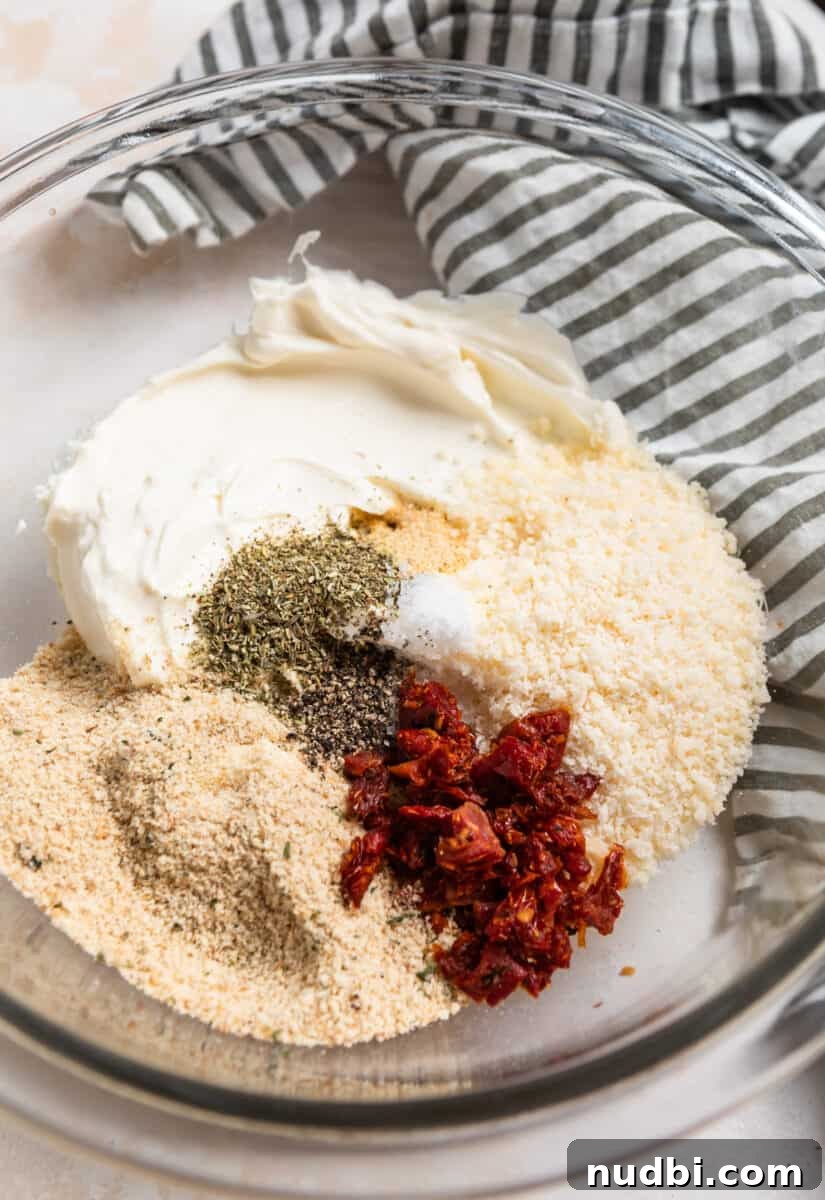 Crispy Air Fryer Stuffed Mushrooms Recipe for Quick Appetizers 4 Cream cheese, parmesan, sun-dried tomatoes, and other ingredients in glass mixing bowl.