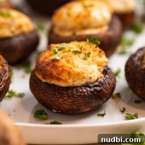 Crispy Air Fryer Stuffed Mushrooms Recipe for Quick Appetizers 9 Air fried stuffed mushrooms on white plate topped with chopped parsley.