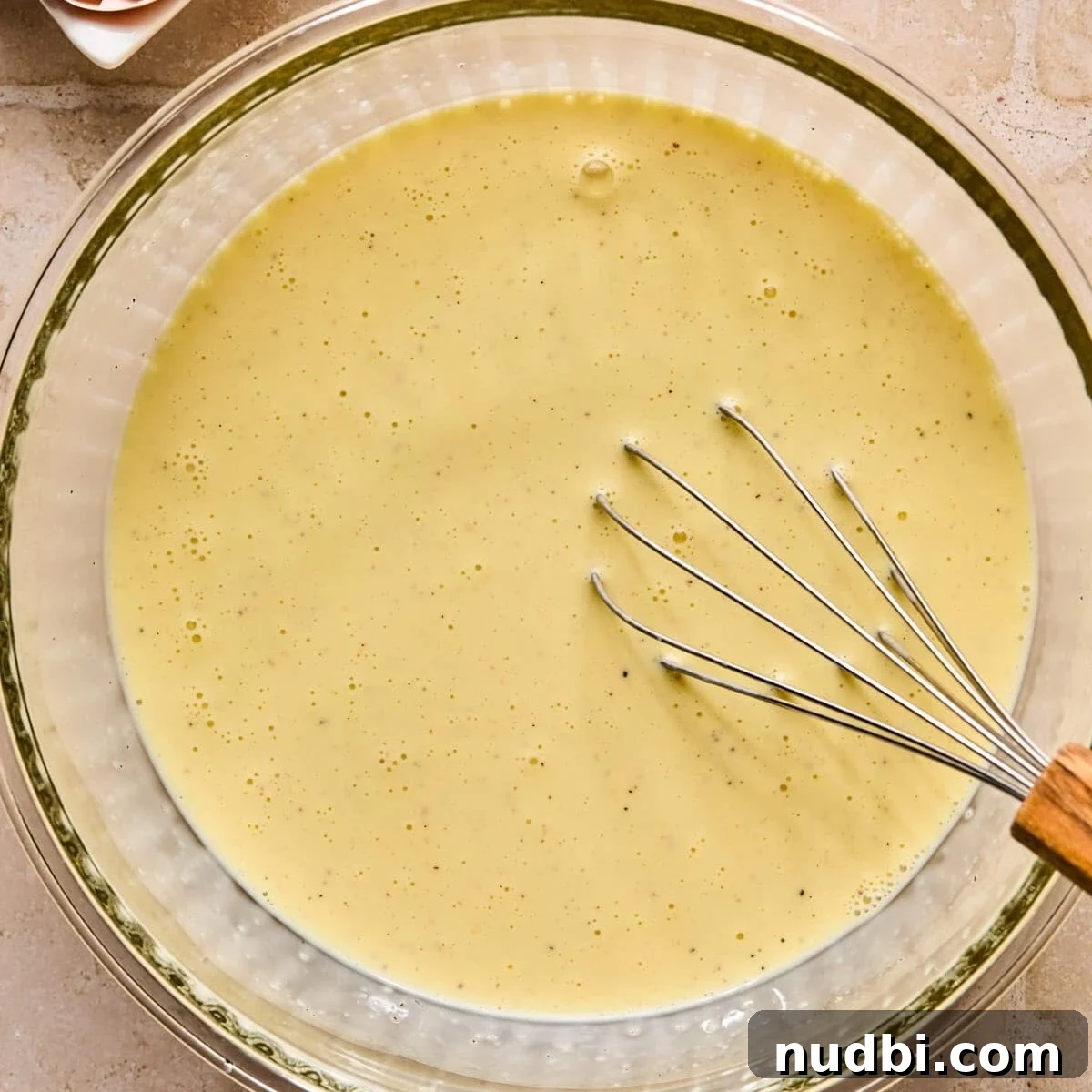 Flaky Puff Pastry Quiche Recipe: Quick Savory Tart for Brunch 6 Egg, milk and cream mixture in glass bowl with whisk.