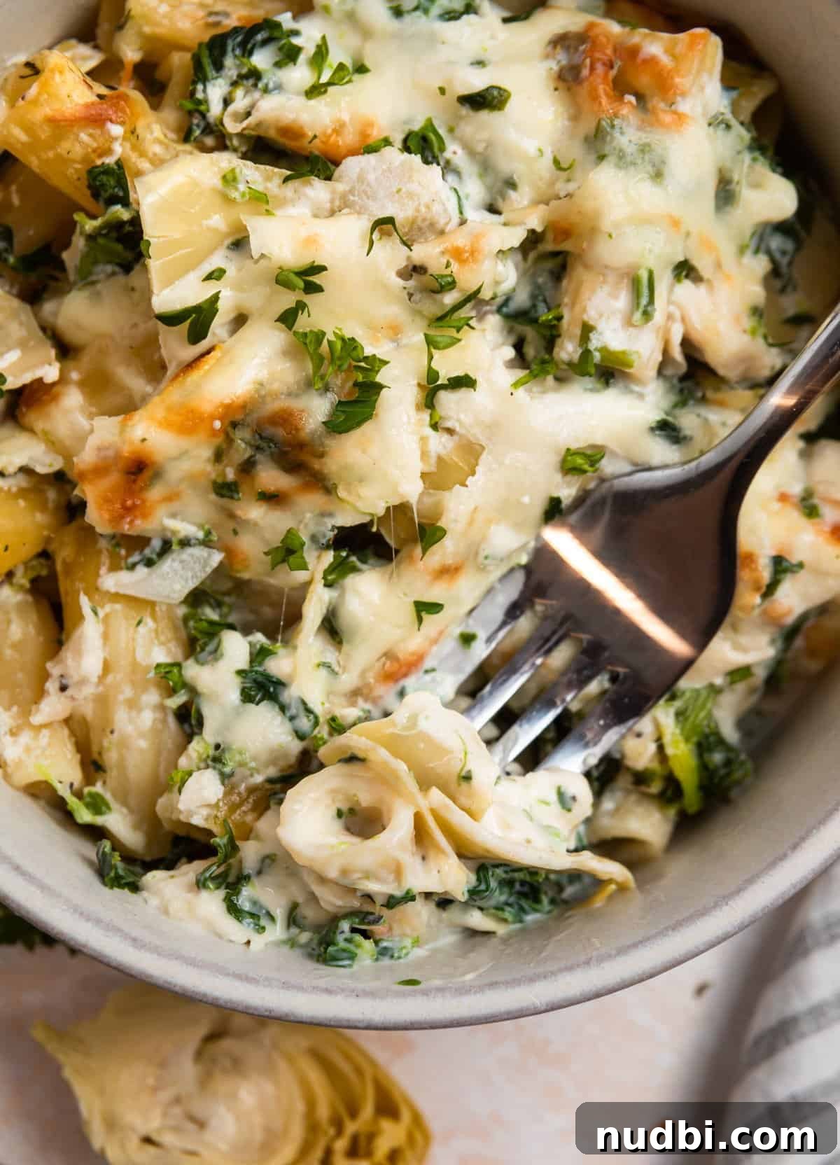 Spinach and Artichoke Chicken Casserole Recipe 2 Bowl of spinach artichoke chicken casserole with forkful of the recipe.