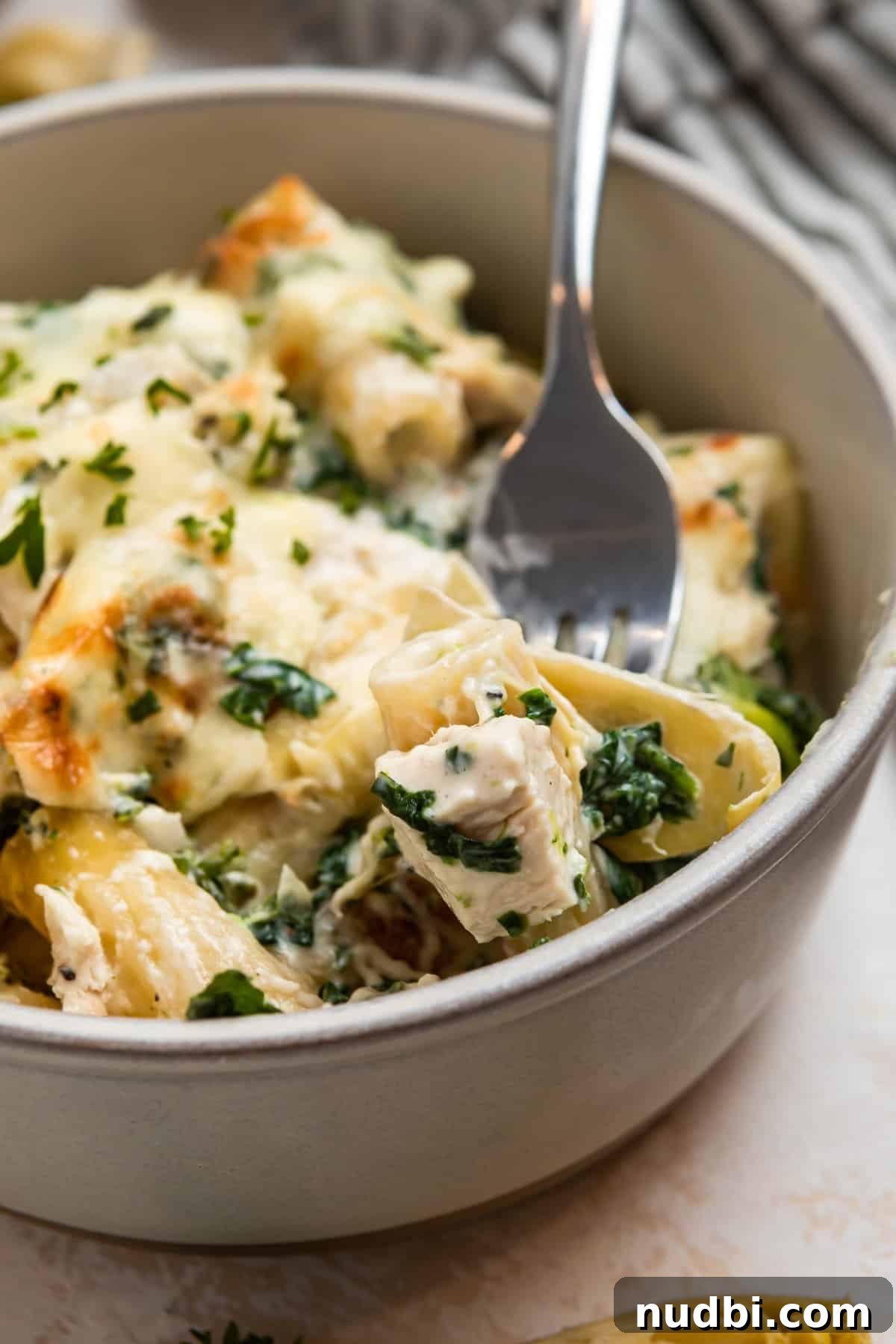 Spinach and Artichoke Chicken Casserole Recipe 11 Spinach, chicken artichoke pasta casserole in bowl with fork.