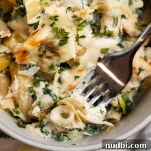 Spinach and Artichoke Chicken Casserole Recipe 12 Chicken spinach and artichoke pasta casserole in dish with fork.