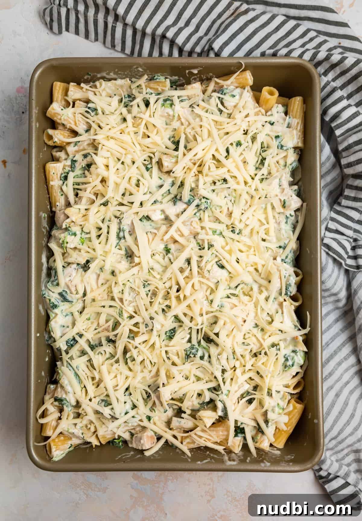 Spinach and Artichoke Chicken Casserole Recipe 9 Casserole dish with shredded cheese on top.