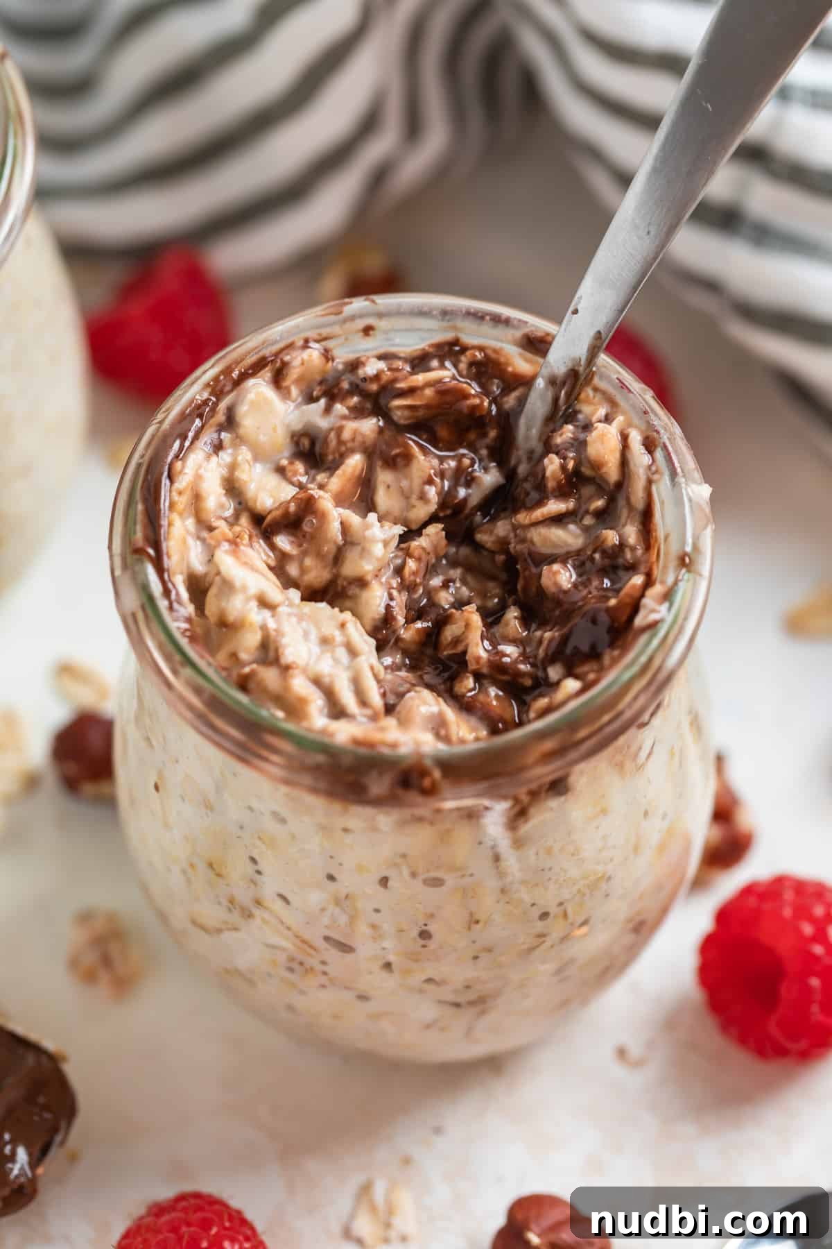 Creamy Nutella Overnight Oats Recipe for Quick Morning Meals 4 Nutella overnight oats in jar with spoon scooped into it.