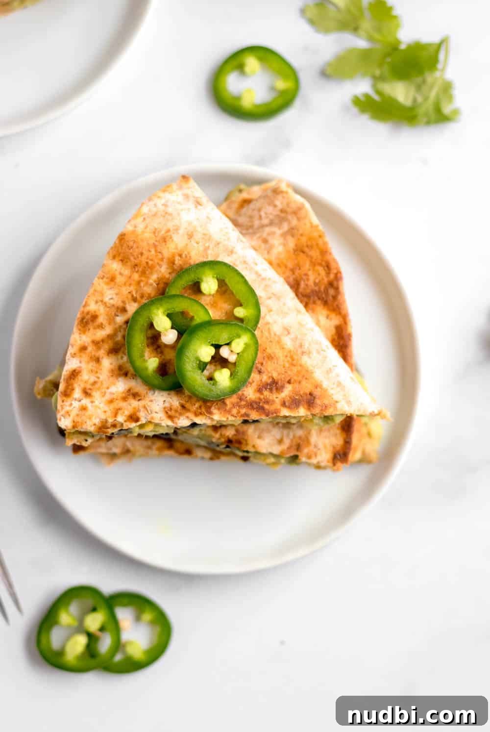 Vegan Black Bean and Avocado Quesadillas Recipe 2 Black bean and avocado quesadilla on white plate with jalapeno.