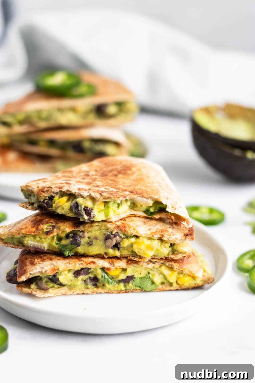 Vegan Black Bean and Avocado Quesadillas Recipe 4 Bite shot of Vegan Black Bean quesadillas with avocado on white plate.