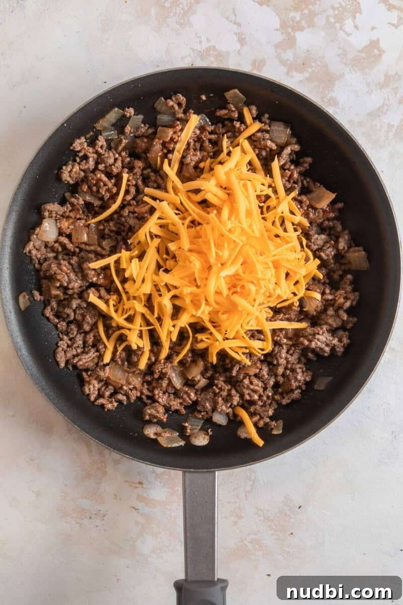 Cheeseburger-Stuffed Potato Skins: Loaded Appetizer Recipe 8 Cheese topped ground beef in skillet.