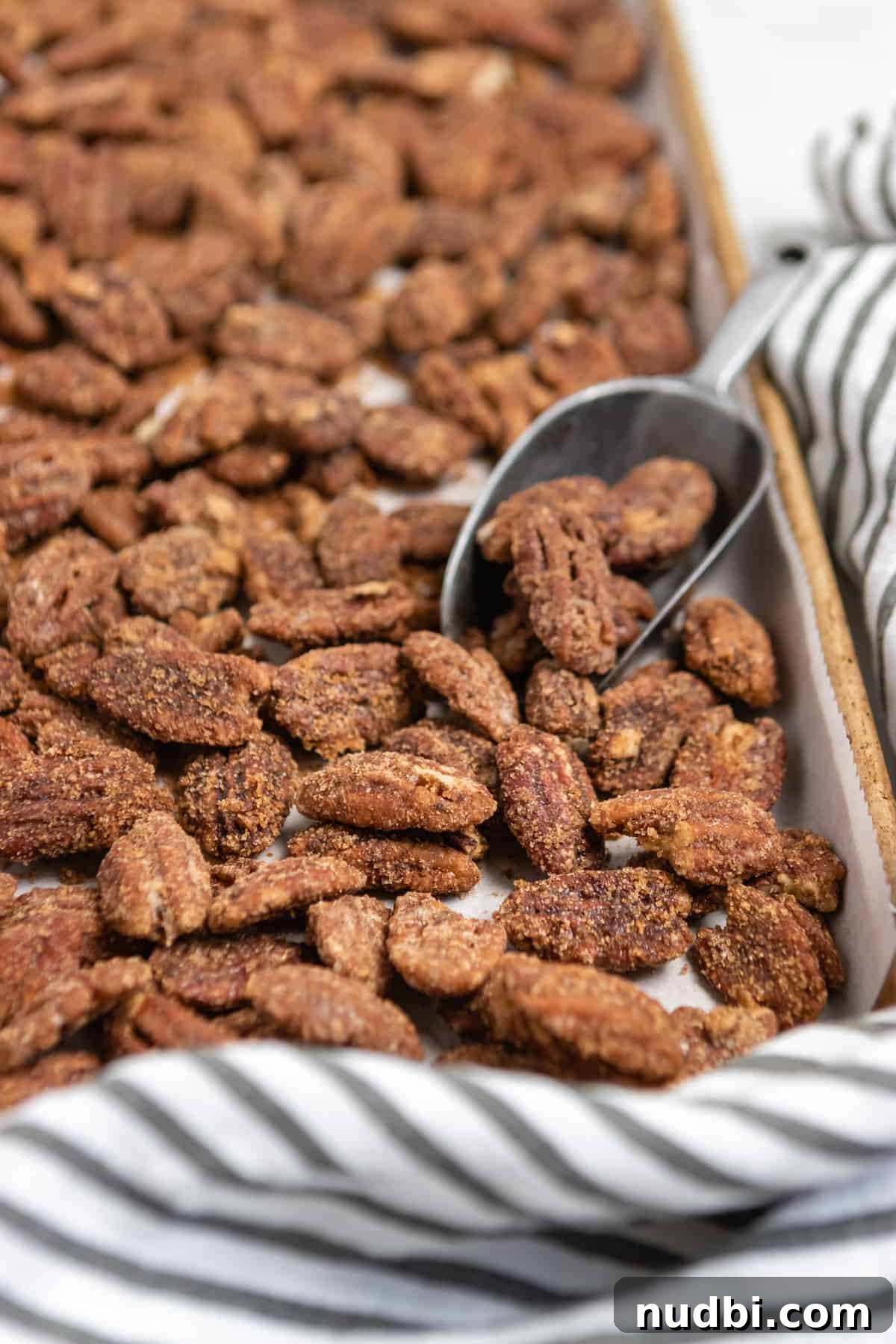 Candied Pumpkin Spice Pecans Made in a Slow Cooker 2 Sheet pan with pumpkin spiced cinnamon pecans and scoop.