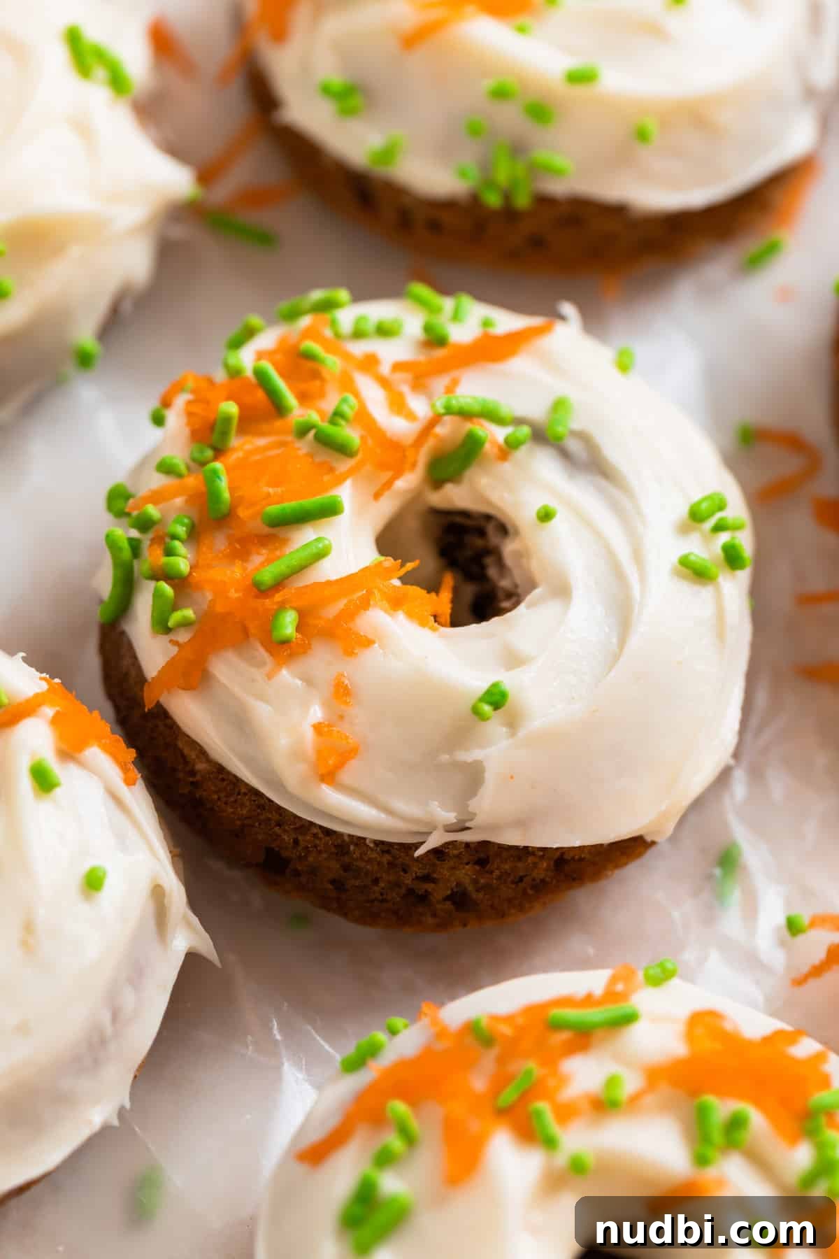 Carrot Cake Donuts with Cream Cheese Glaze: Moist Spiced Recipe 2 Carrot cake baked donuts with cream cheese frosting topped with shredded carrots and green sprinkles.