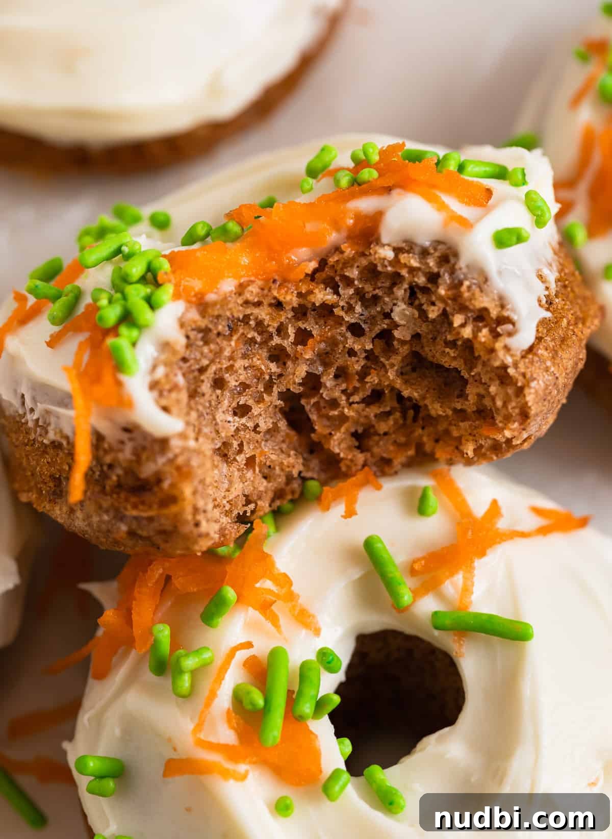 Carrot Cake Donuts with Cream Cheese Glaze: Moist Spiced Recipe 10 Carrot cake donut with cream cheese frosting with bite taken out.