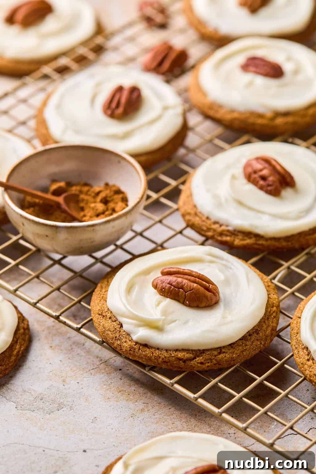 Pumpkin Spice Molasses Cookies Recipe with Warm Autumn Flavor 2 Molasses cookies on cooling rack with icing and pecan on top.