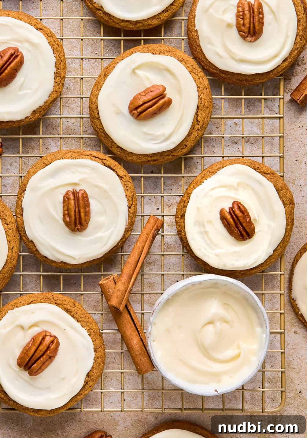 Pumpkin Spice Molasses Cookies Recipe with Warm Autumn Flavor 15 Maple cream cheese frosted pumpkin spice molasses cookies on cooling rack with cinnamon sticks.