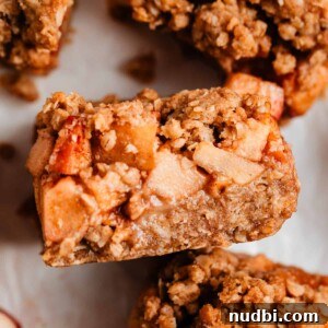 Homemade Apple Crumble Bars Recipe — Soft Filling & Crunchy Topping 9 Apple crumble bar propped on surrounding sliced bars.