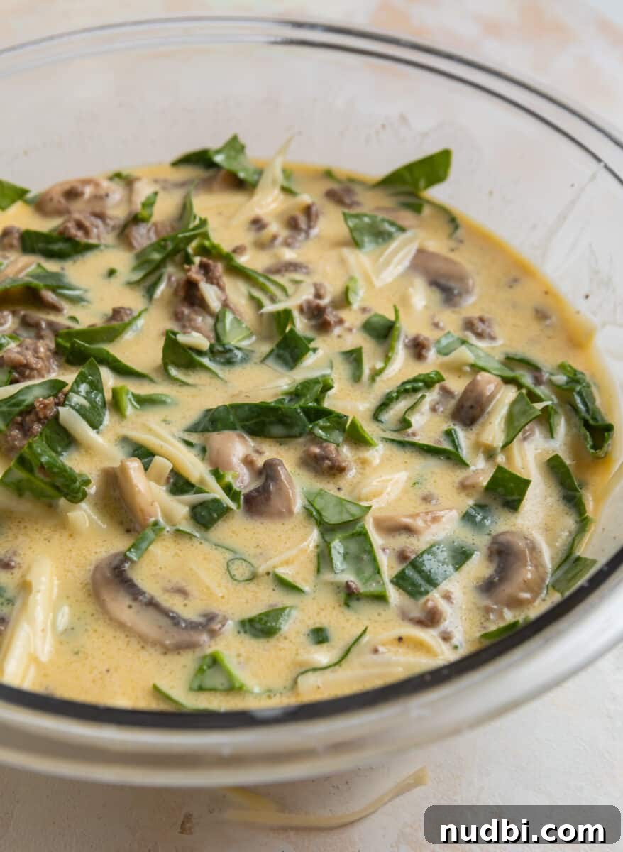 Savory Crustless Mushroom and Cheese Quiche Recipe 7 Quiche ingredients in mixing bowl including meat, spinach, mushrooms, swiss cheese, eggs, cream and milk.