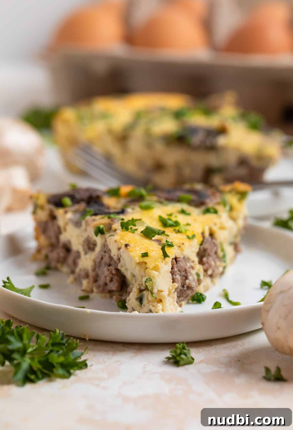 Savory Crustless Mushroom and Cheese Quiche Recipe 10 Beef, swiss and mushroom crustless quiche slice on white plate.