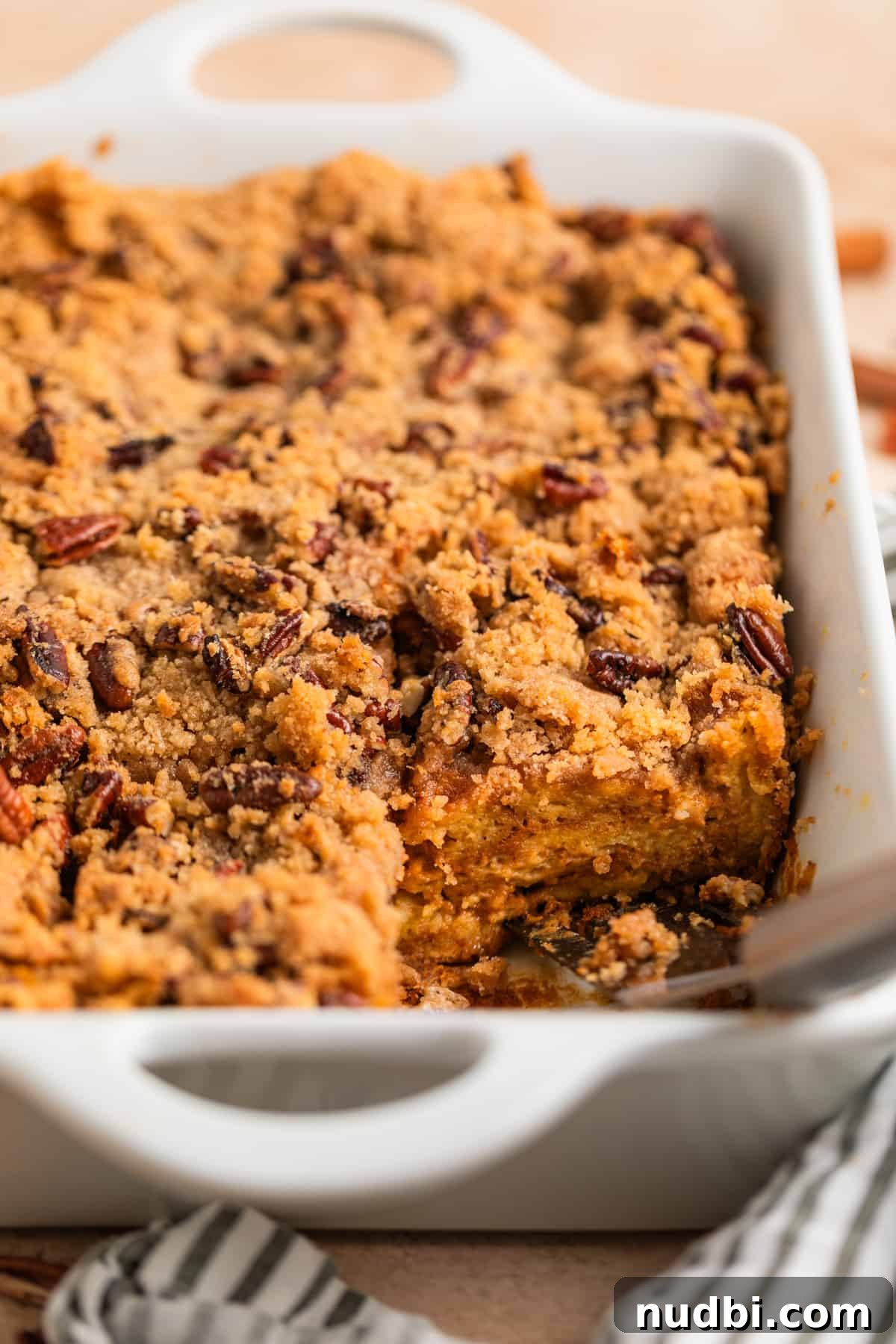 Pumpkin Spice French Toast Casserole Recipe for Fall Brunch 2 Pumpkin spice French toast casserole in white dish with spatula set where one slice has been removed.
