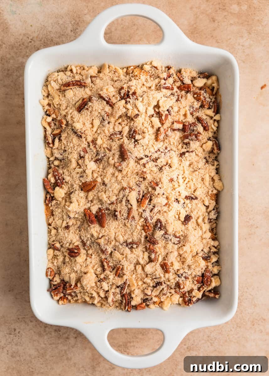 Pumpkin Spice French Toast Casserole Recipe for Fall Brunch 9 Streusel pecan topping sprinkled over French toast casserole mixture in pan.
