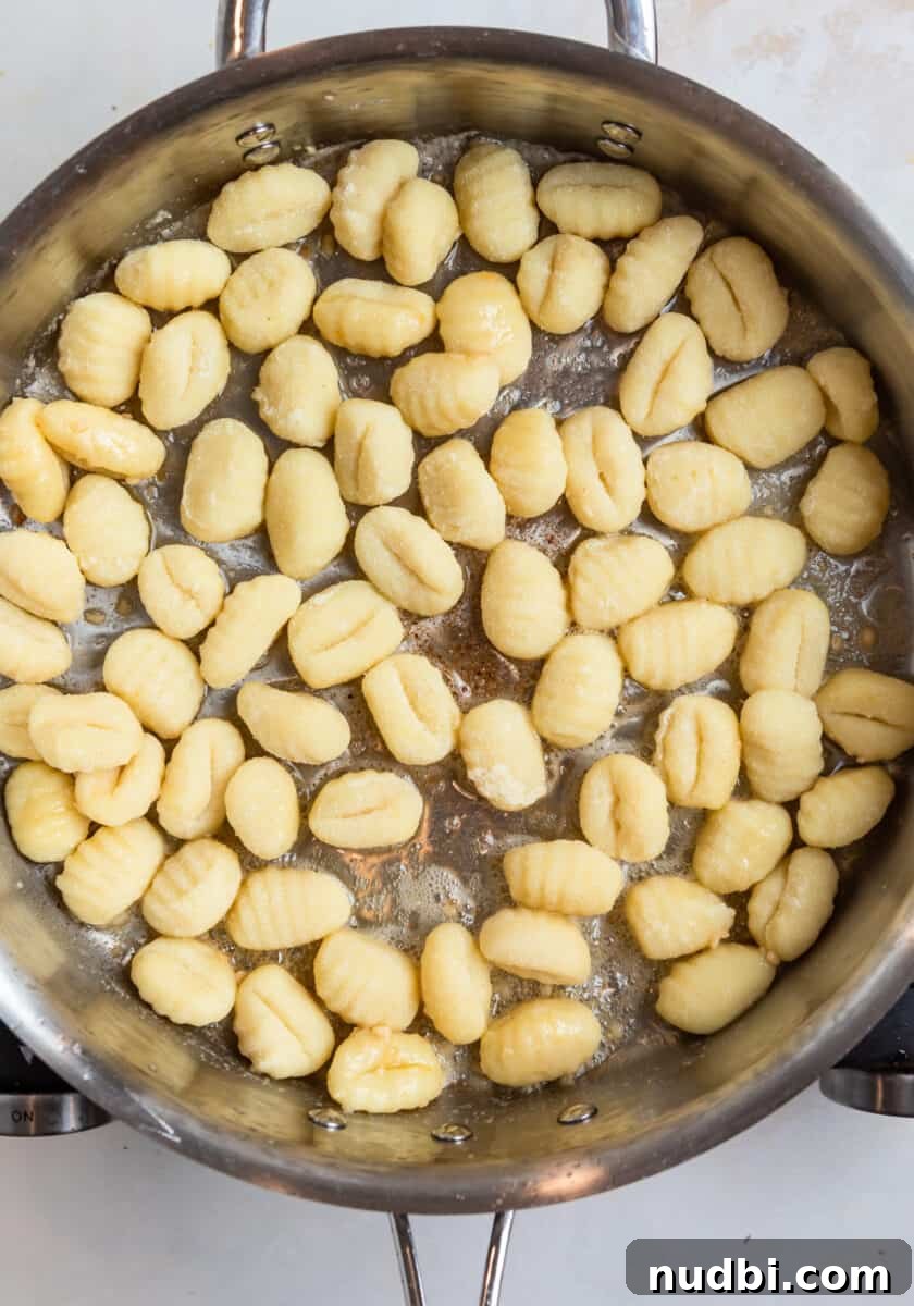 Crispy Pan-Fried Gnocchi with Garlic Butter and Parmesan 5 Uncooked gnocchi in silver skillet with butter.