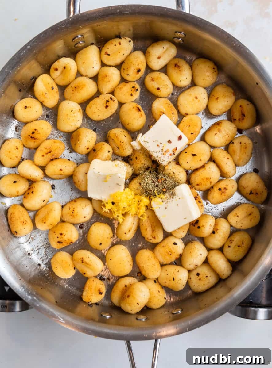 Crispy Pan-Fried Gnocchi with Garlic Butter and Parmesan 7 Butter, lemon zest and seasoning added to pan of gnocchi.