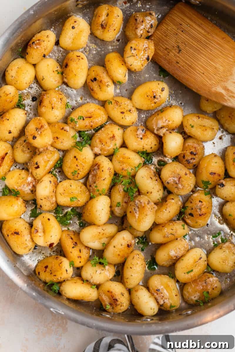 Crispy Pan-Fried Gnocchi with Garlic Butter and Parmesan 9 Gnocchi in skillet with parmesan, garlic and chopped parsley.