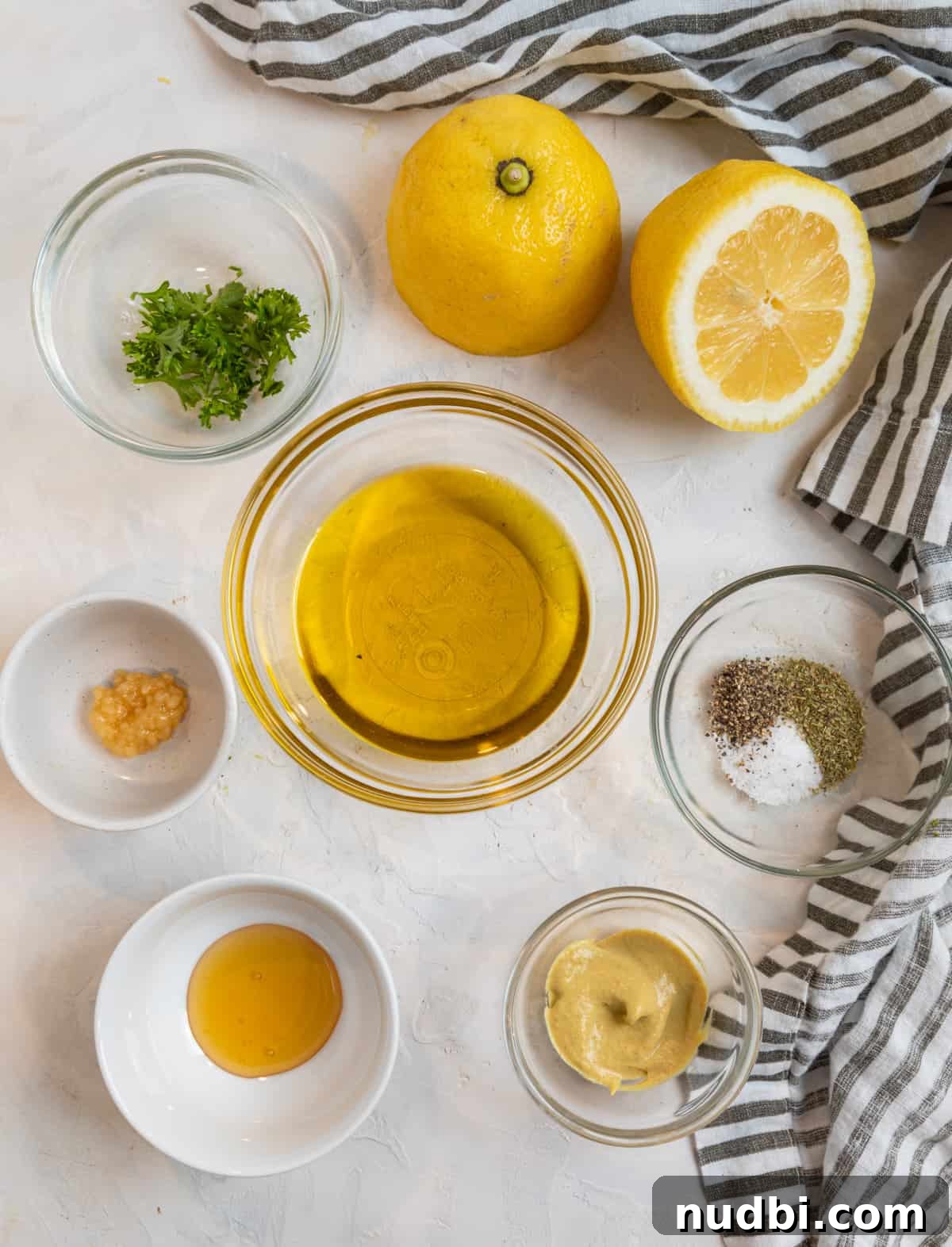 Zesty Lemon Dijon Salad Dressing Recipe 3 Lemon, olive oil, garlic, honey and other ingredients needed for recipe on counter.