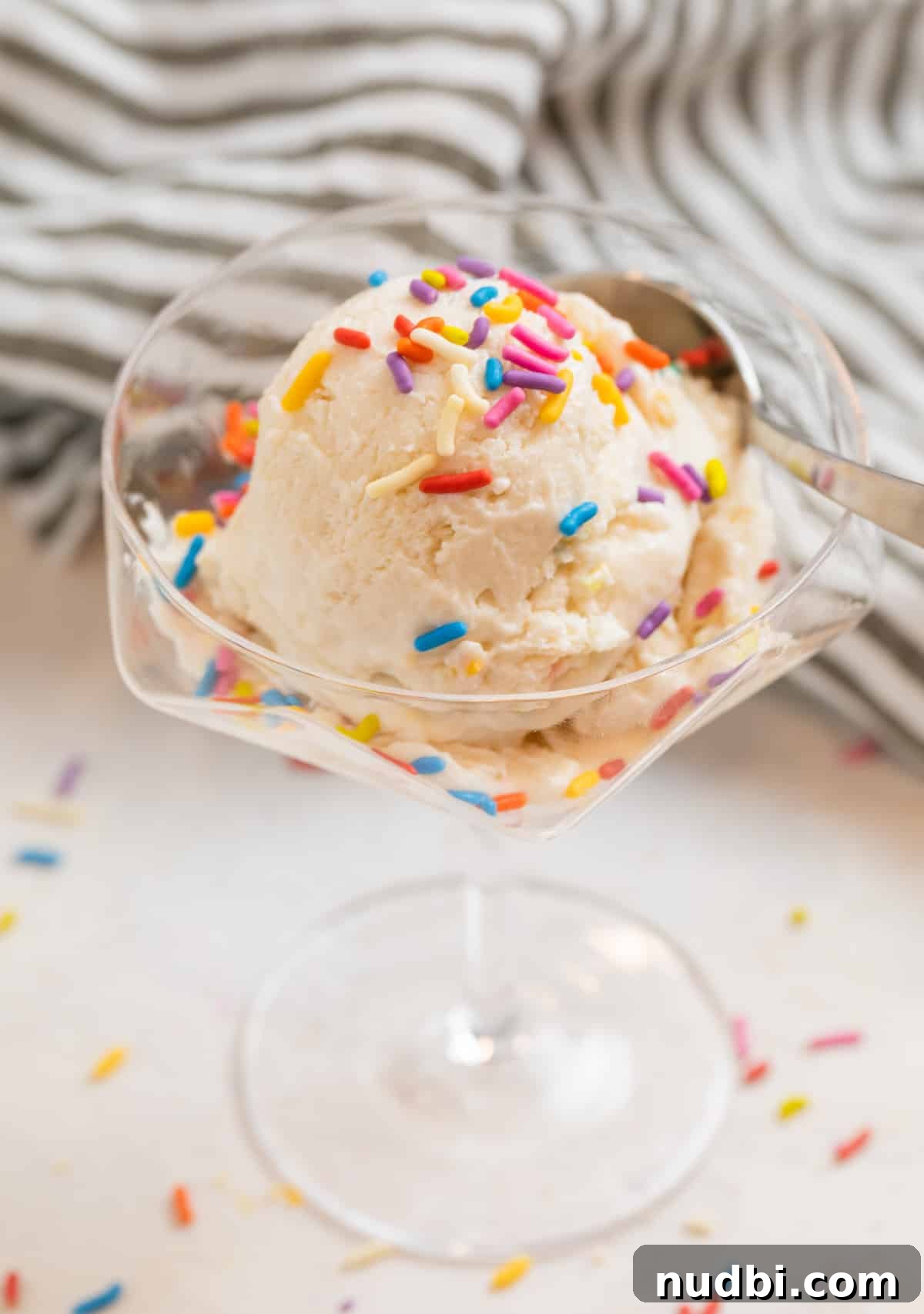 Creamy Cottage Cheese Ice Cream Recipe — Low-Sugar Frozen Dessert 12 Vanilla ice cream in glass dessert dish with spoon and rainbow sprinkles on top.