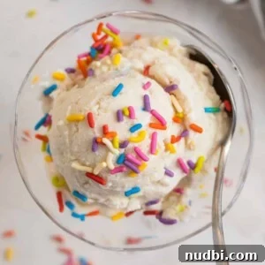 Creamy Cottage Cheese Ice Cream Recipe — Low-Sugar Frozen Dessert 13 Scoop of cottage cheese ice cream in glass bowl with spoon and rainbow sprinkles on top.