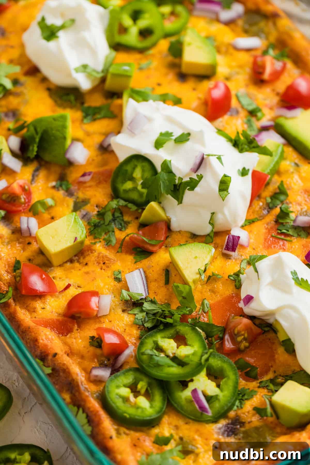 Cheesy Chorizo and Egg Breakfast Casserole 9 Pan with chorizo egg bake topped with sour cream, onion, jalapeño, and other toppings.