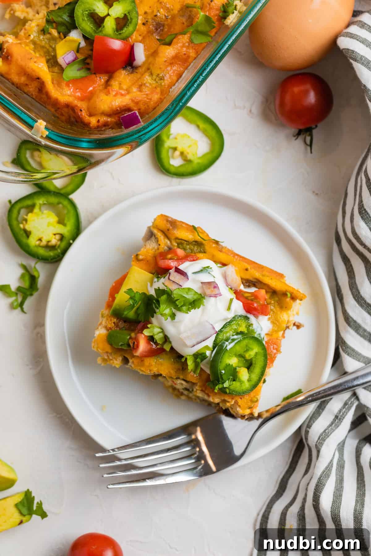 Cheesy Chorizo and Egg Breakfast Casserole 10 Slice of breakfast casserole on white plate with fork and napkin beside it.