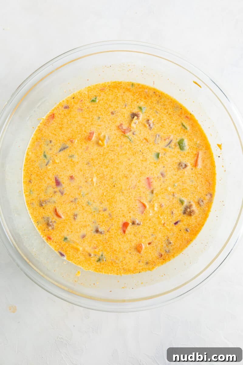 Cheesy Chorizo and Egg Breakfast Casserole 7 Sausage and peppers added to glass mixing bowl with eggs.
