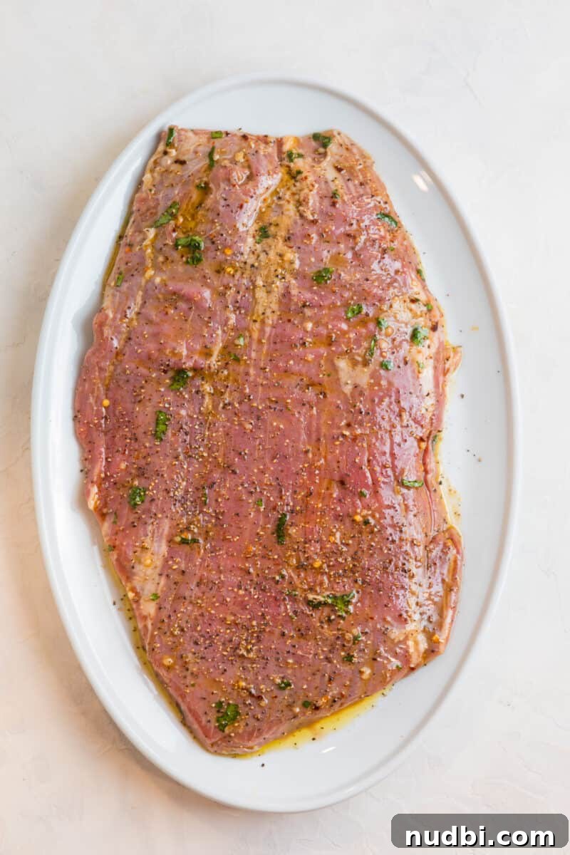 Grilled Flank Steak Salad with Chimichurri and Arugula 7 Marinated flank steak on white plate.