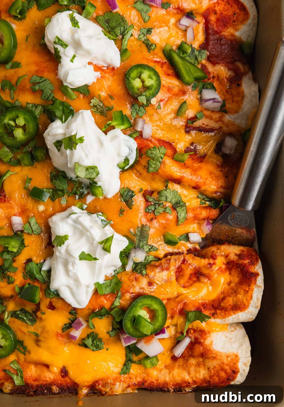 Cheesy Ground Turkey Enchiladas with Homemade Red Sauce 2 Ground turkey enchiladas in pan topped with cheese, jalapeños, cilantro and more.