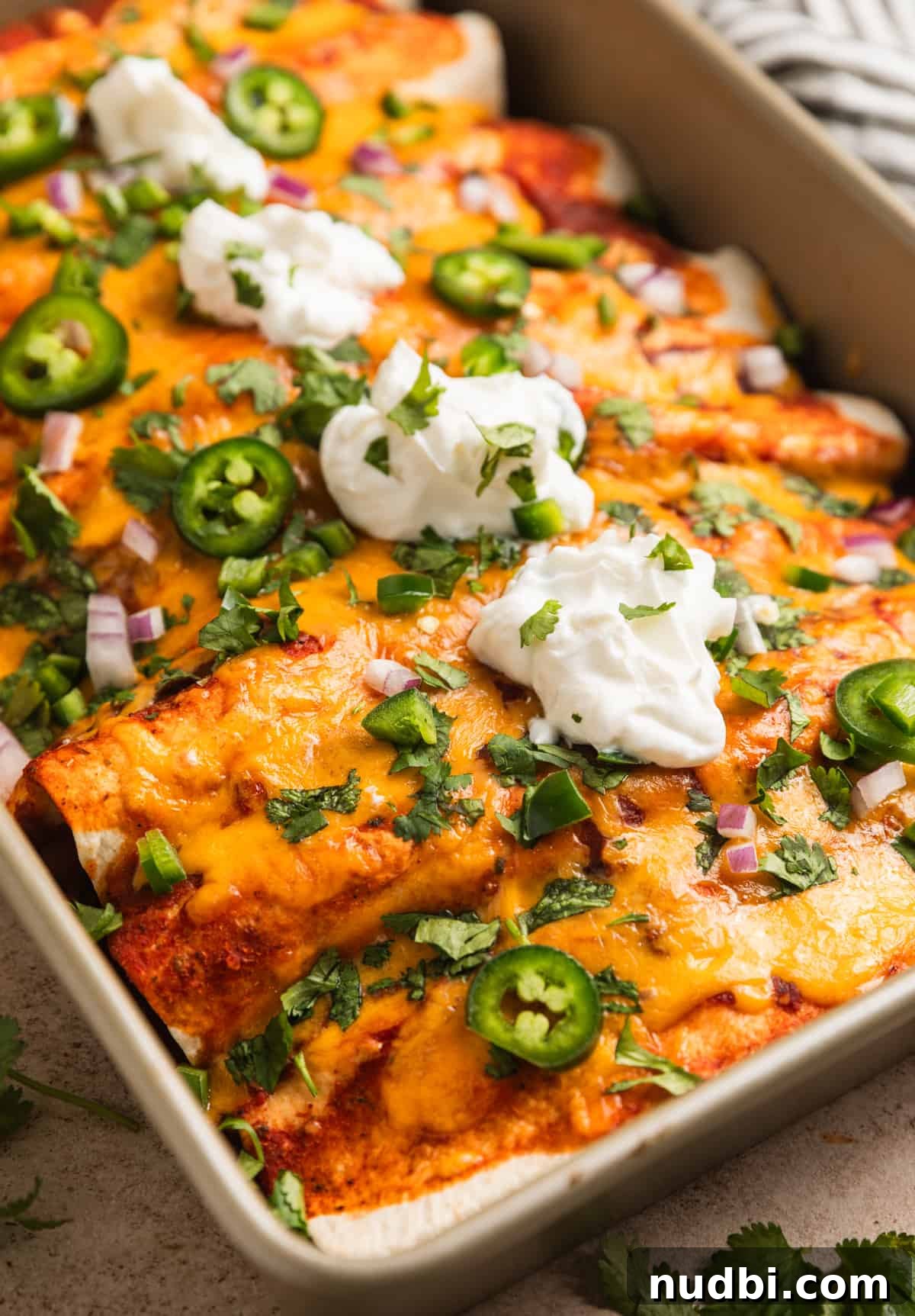 Cheesy Ground Turkey Enchiladas with Homemade Red Sauce 3 Pan of enchiladas topped with sour cream and cilantro.