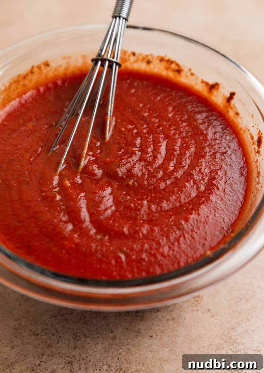 Cheesy Ground Turkey Enchiladas with Homemade Red Sauce 7 Enchilada sauce in glass bowl with whisk.