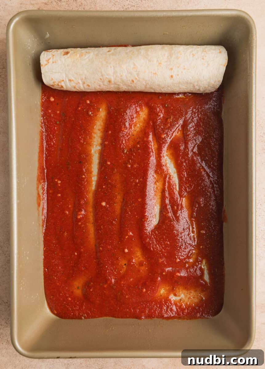Cheesy Ground Turkey Enchiladas with Homemade Red Sauce 10 Rolled enchilada in pan with enchilada sauce on bottom of pan.
