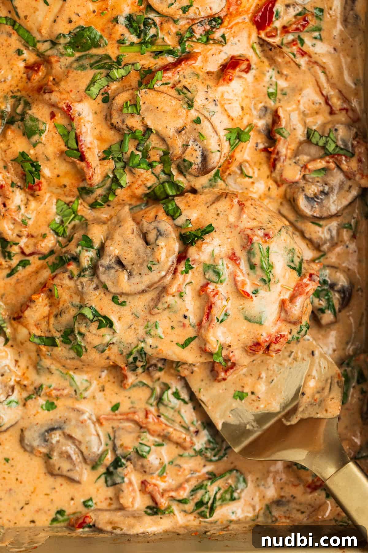 Creamy Baked Tuscan Chicken with Sun-Dried Tomatoes and Spinach 3 Baked chicken with cream sauce over top with mushrooms, spinach, sun-dried tomatoes, and parsley over top.