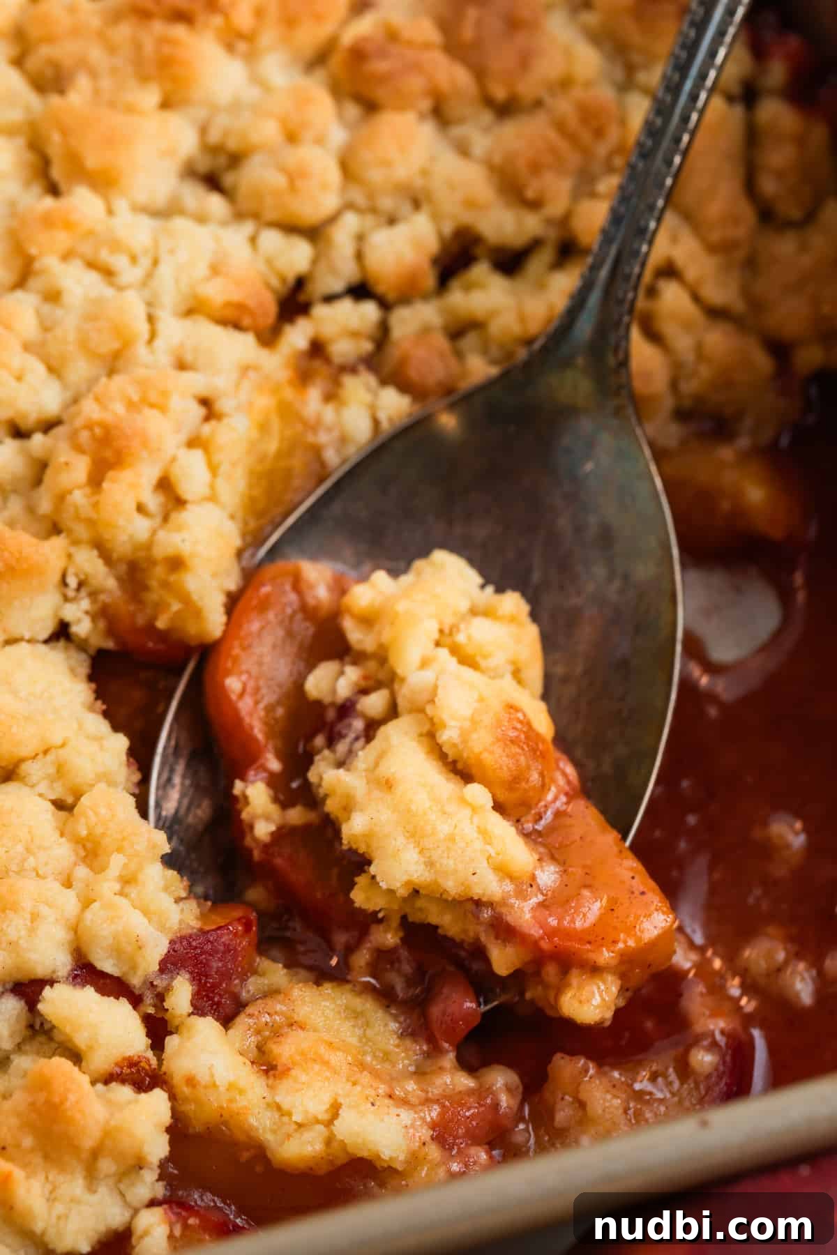 Peach Cobbler Made with Cake Mix: Quick Southern Dessert recipe 3 Cake mix peach cobbler in baking pan with serving spoon.