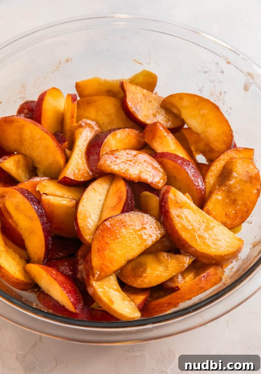 Peach Cobbler Made with Cake Mix: Quick Southern Dessert recipe 5 Peaches tossed with cinnamon, sugar and other ingredients in glass mixing bowl.