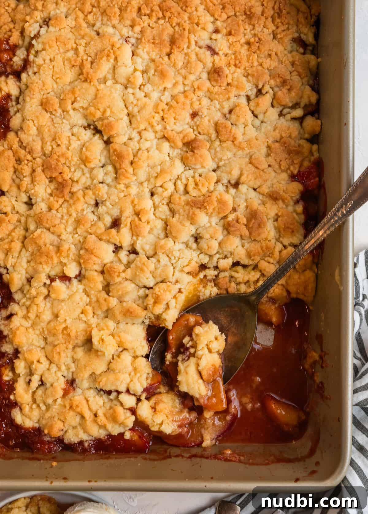 Peach Cobbler Made with Cake Mix: Quick Southern Dessert recipe 10 Cake mix peach cobbler in baking pan with spoon scooping out a section.
