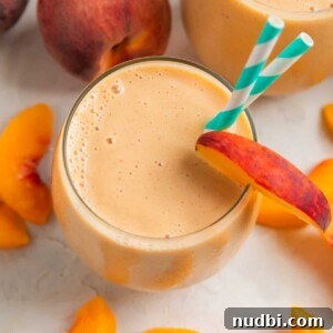 Creamy Banana and Peach Smoothie Recipe for Summer Refreshment 6 Peach banana smoothie in glass with peach slices surrounding.