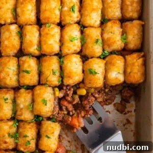Tater Tot Shepherd’s Pie Recipe: Comforting Family Meal 15 Pan with tater tot shepherds pie with serving utensil scooping in.