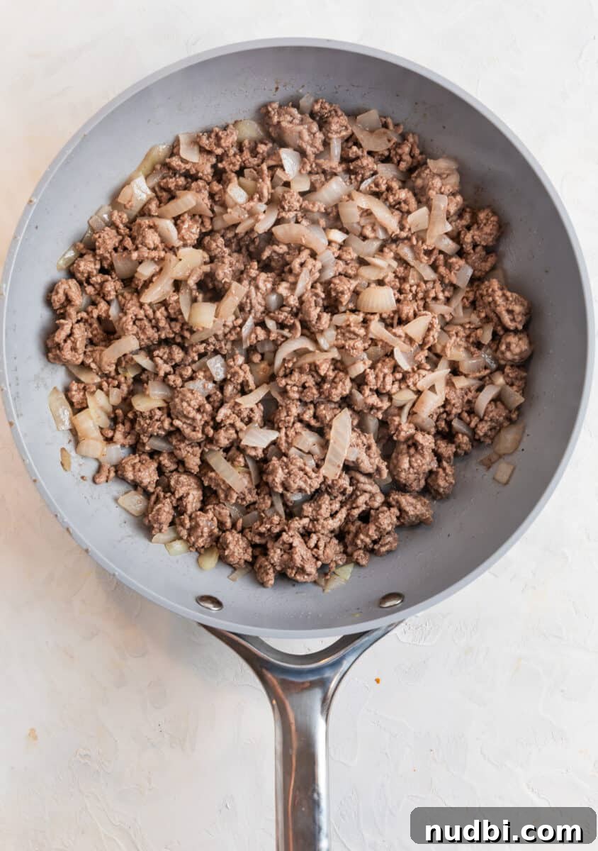 Tater Tot Shepherd’s Pie Recipe: Comforting Family Meal 4 Ground beef and onions cooked in gray skillet.