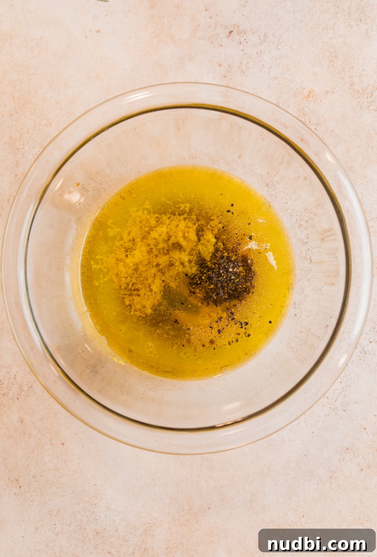 Crispy Lemon Pepper Pork Chops with Garlic Butter Sauce 4 Lemon pepper marinade ingredients in glass mixing bowl.