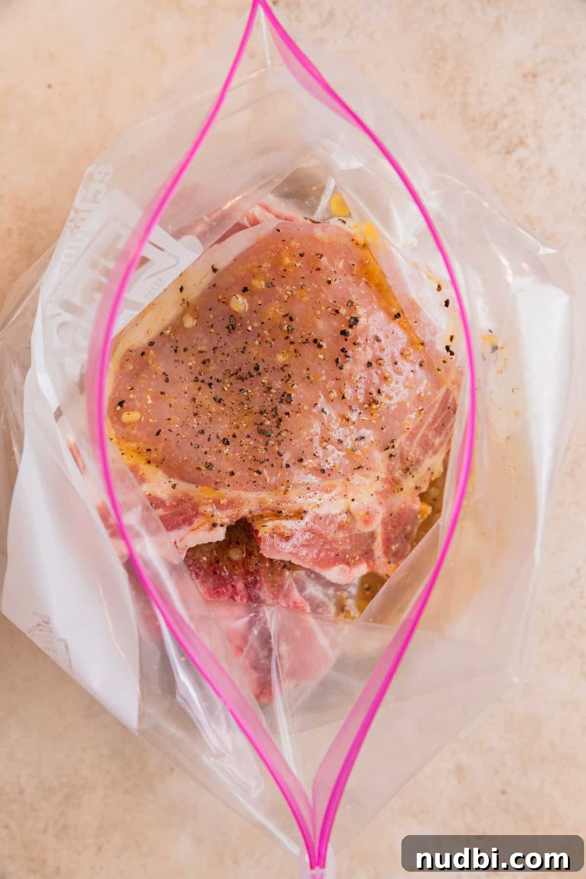Crispy Lemon Pepper Pork Chops with Garlic Butter Sauce 5 Raw pork chops in plastic bag with lemon pepper marinade over top.