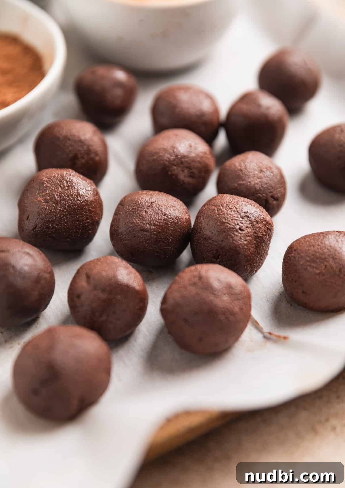 Amaretto Truffles Recipe with 5 Ingredients — Simple Chocolate Bonbons 9 Chocolate truffles rolled and laying on parchment paper.