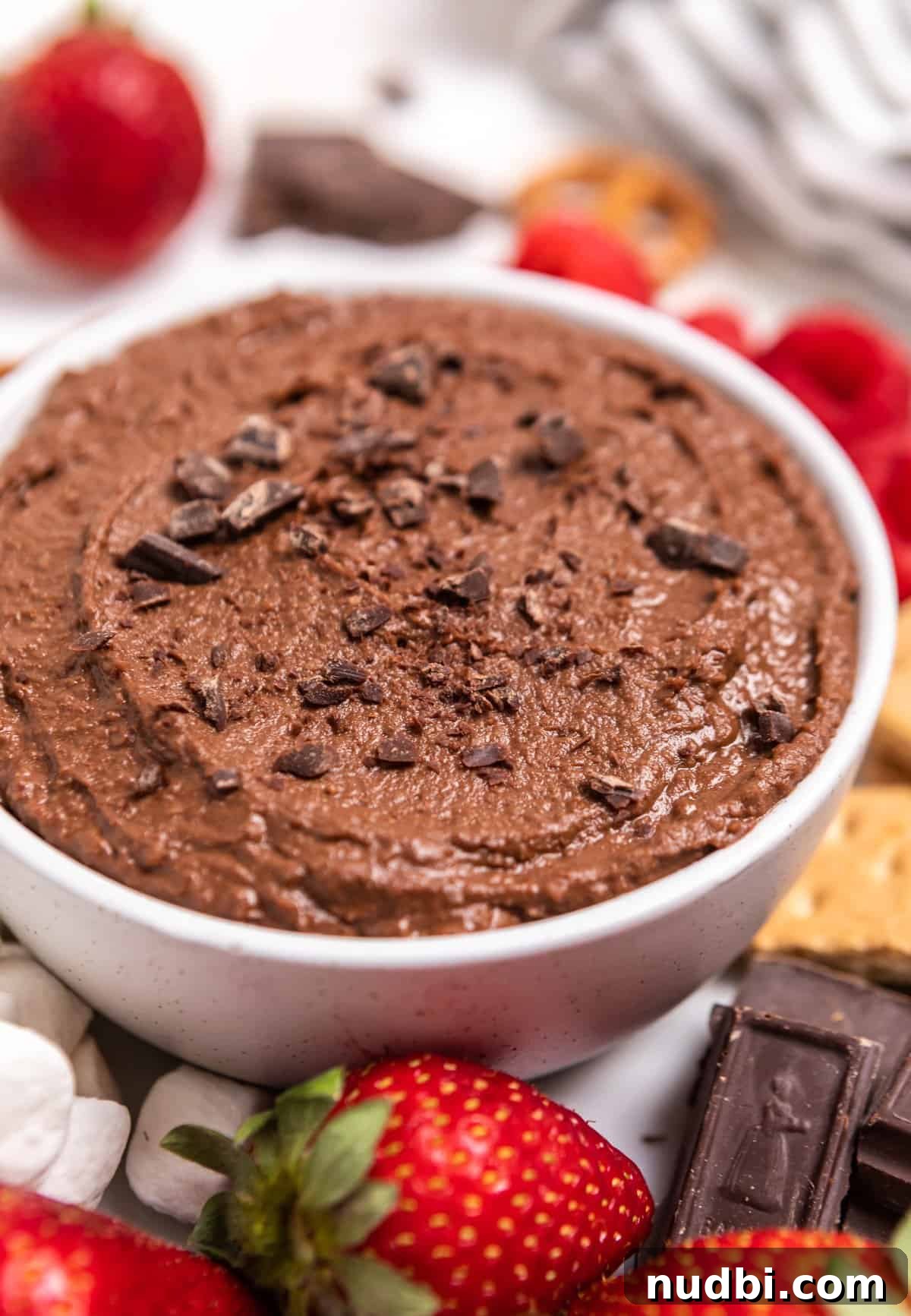 Decadent Brownie Batter Hummus Recipe: Dessert Dip Made Vegan 6 White bowl with brownie batter dessert hummus surrounded by berries and other dippers.
