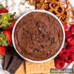 Decadent Brownie Batter Hummus Recipe: Dessert Dip Made Vegan 7 White bowl with chocolate brownie batter hummus on plate with berries, graham crackers and other dippers.